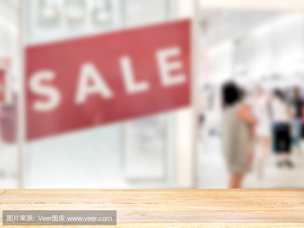 空的棕色木桌和模糊的服装店背景与商店的销售标志,可用于蒙太奇或展示您的产品